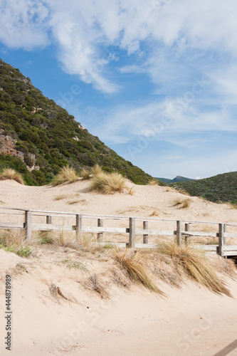 Wooden path to the sea with sand dunes and mountains