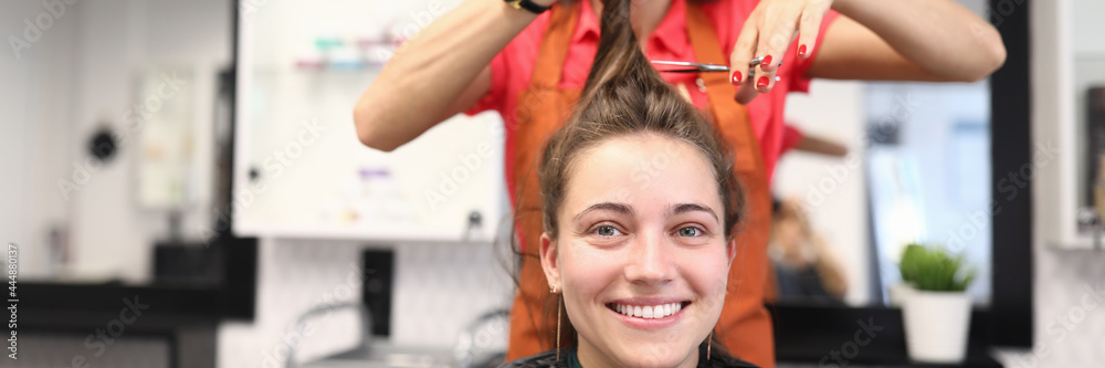 Portrait of smiling woman in hairdressing salon, which master cuts her hair