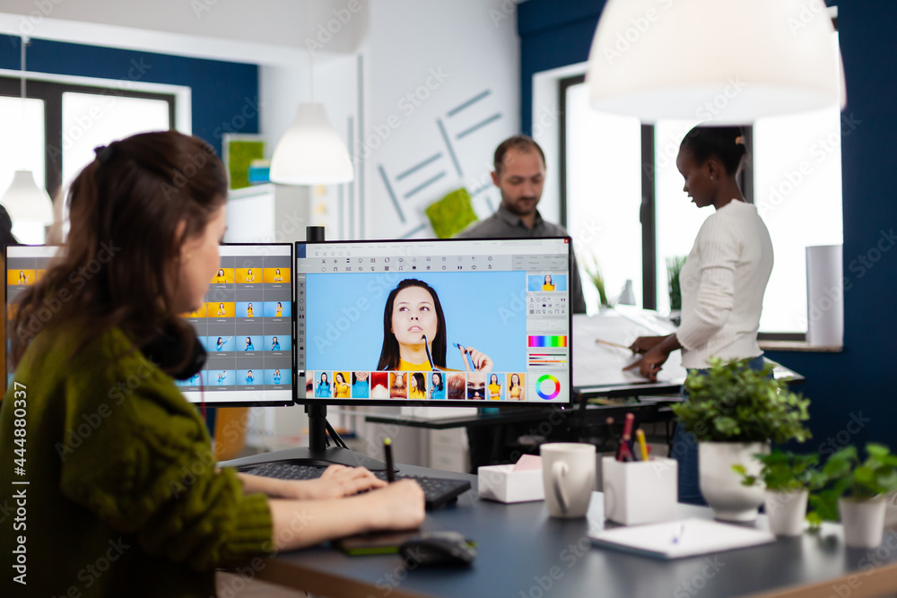 Female photographer edits photos in creative media agency office retouching client imagine with stylus pencil on computer. Freelancer graphic editor working in start up office with digital photos