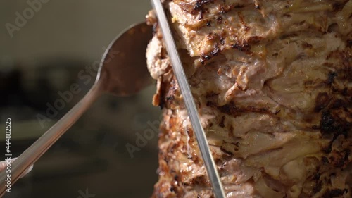 the chef cuts the shawarma on a spit with a large knife