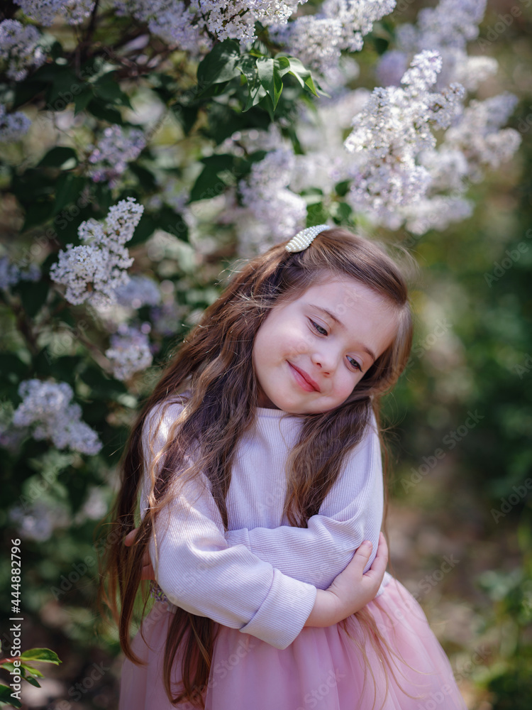 a little girl in a pink dress walking in a lilac garden a little girl in a pink dress walking in a lilac garden