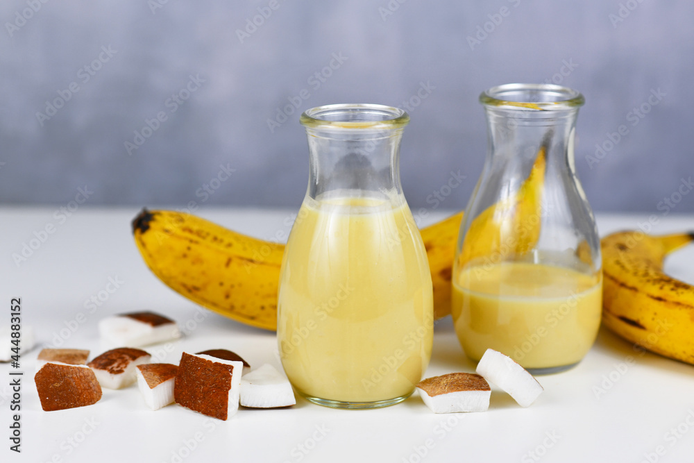 Healthy yellow banana and coconut smoothie drink in jars next to ingredients Healthy yellow banana and coconut smoothie drink in jars next to ingredients