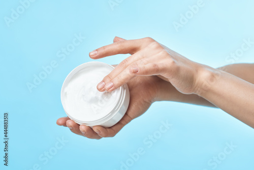 jar of cream in hand skin care close-up cosmetics blue background