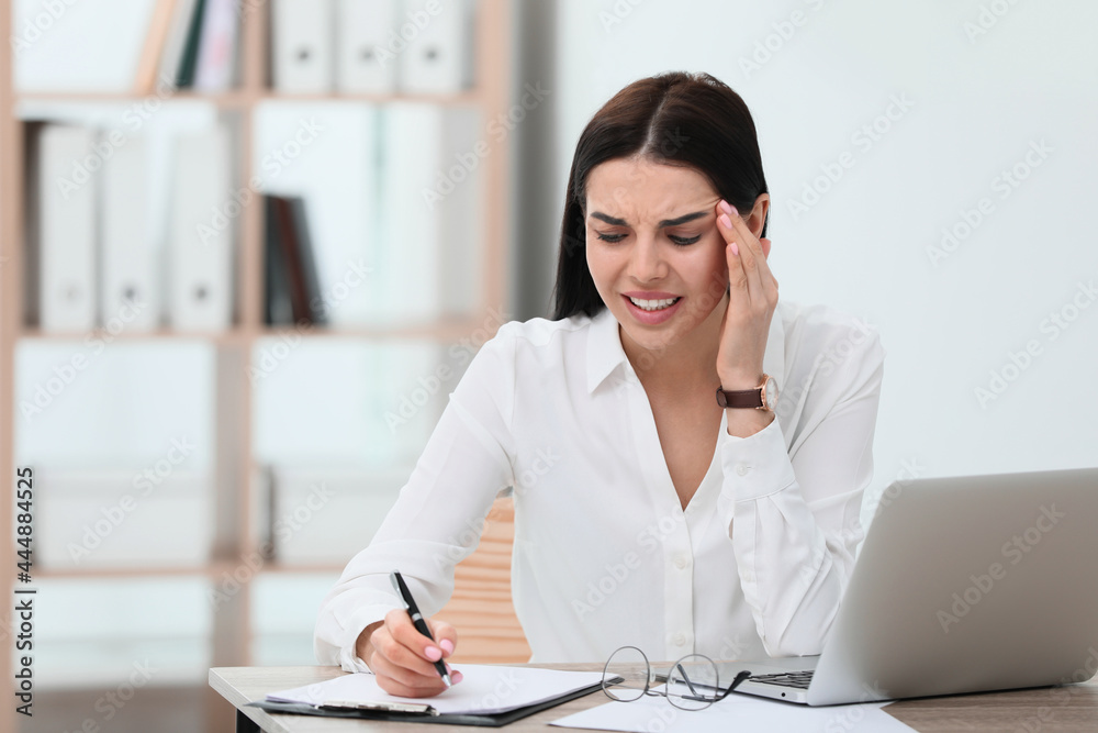 Woman suffering from migraine at workplace in office, space for text Woman suffering from migraine at workplace in office, space for text
