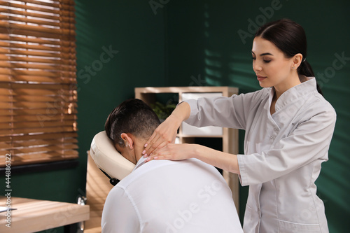 Man receiving massage in modern chair indoors