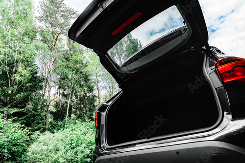 Modern black car with open trunk door on road. photo