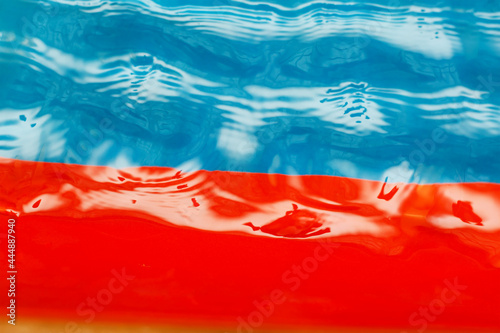 Defocused shot of transparent water against blue and red. Water