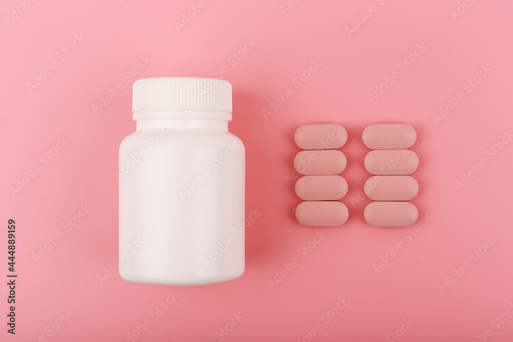 Creative flat lay with white medication bottle and oval pink pills in a row against bright pink background. Concept of supplements and vitamins for pregnant women or for nails and hair growth.  