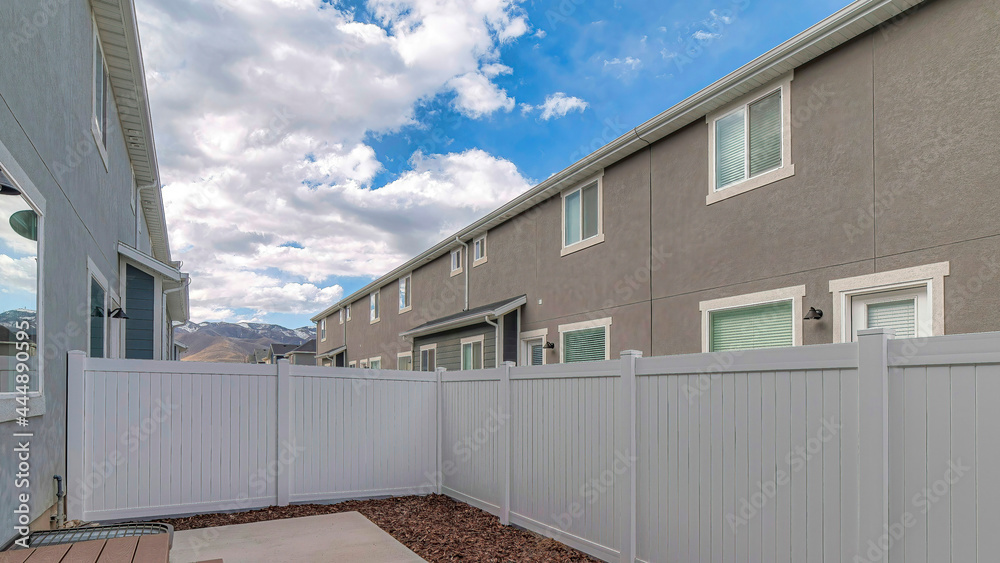 Pano Fully fenced backyard of two storey home with wooden steps leading to glass door