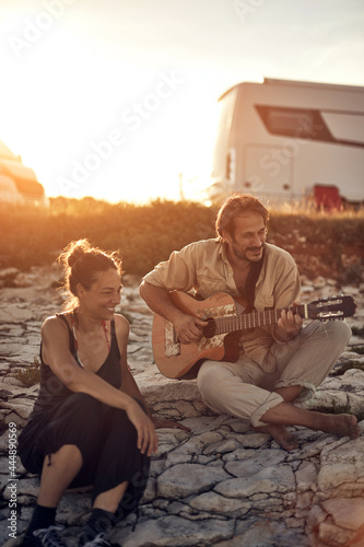 Man singing to his girlfriend on a beach.