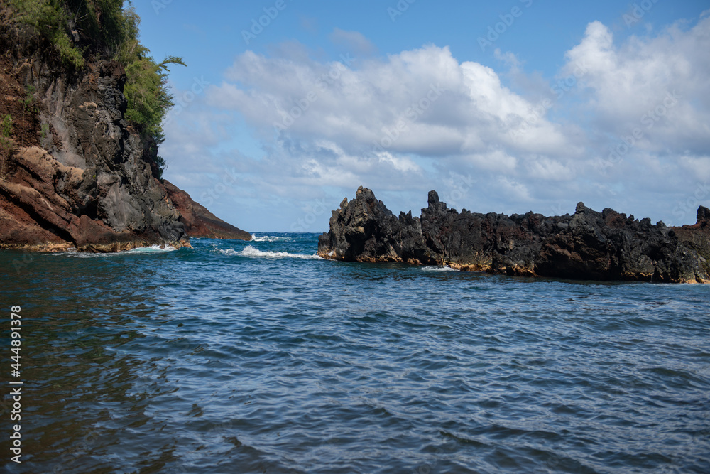Beautiful ocean beach with large rocks on the shore and in the water. Waves in ocean. Summer holidays, vacation.