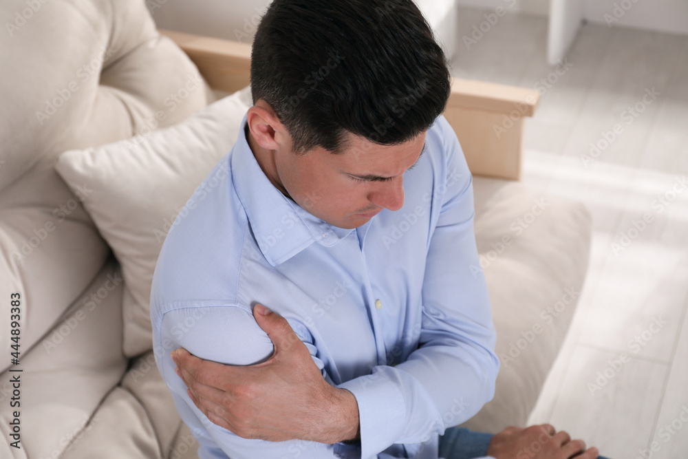Man suffering from shoulder pain at home, closeup Man suffering from shoulder pain at home, closeup