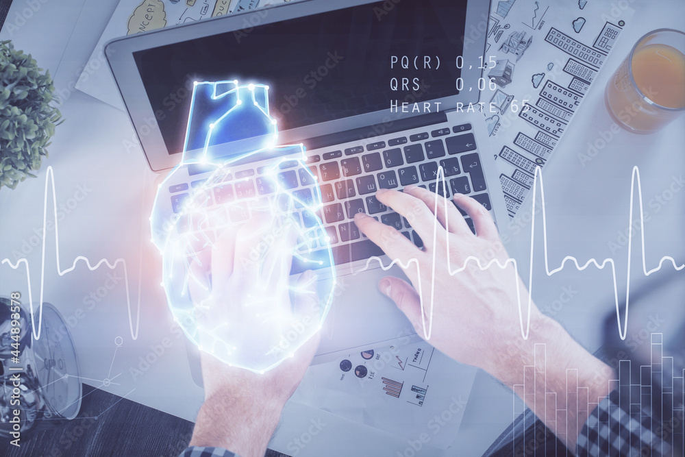 Double exposure of man's hands typing over computer keyboard and human heart hologram drawing. Top view. Medical education concept. Double exposure of man's hands typing over computer keyboard and human heart hologram drawing. Top view. Medical education concept.