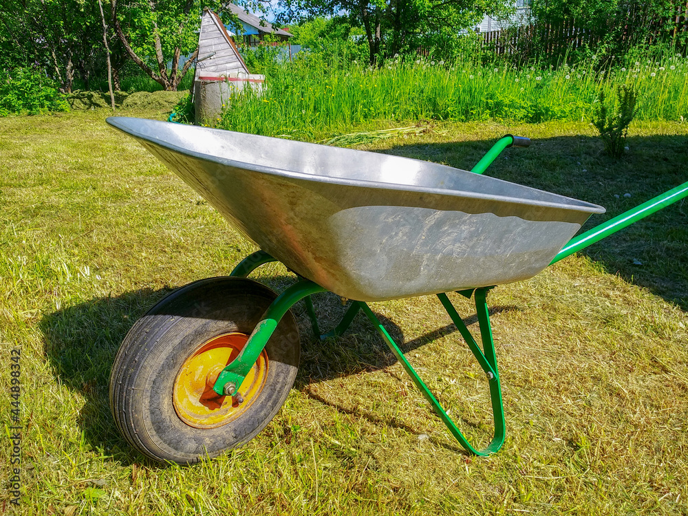 Green vegetable garden. Lawn. Mown grass. Garden wheelbarrow. Gardening Tools. Close-up. Green vegetable garden. Lawn. Mown grass. Garden wheelbarrow. Gardening Tools. Close-up.