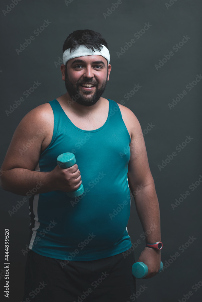 young fat man doing weights on a gray background.
willpower.
effort