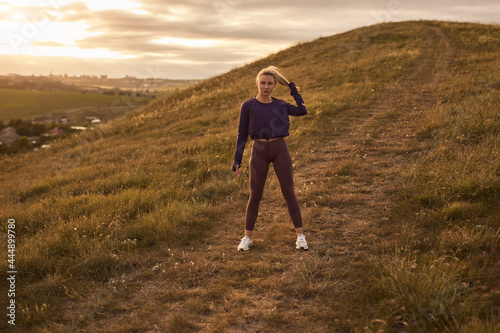 Active woman in sportswear standing on hill