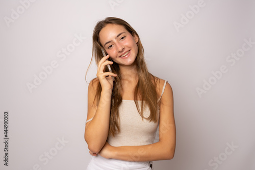 Portrait of a smiling young casual woman talking on mobile phone isolated over white background