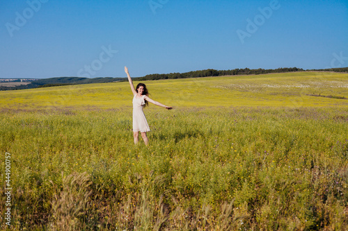 a beautiful woman in a dress walking in a field in nature