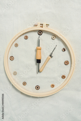 Embriodery hoop, two punch needles and wooden buttons layed as a clock-face. Idea of time, spent for creative hobby. photo