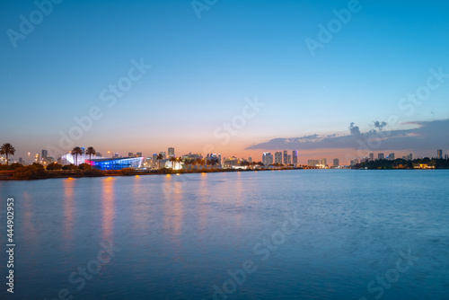 Miami, Florida cityscape skyline on Biscayne Bay. Panorama at dusk with urban skyscrapers and bridge over sea with reflection.
