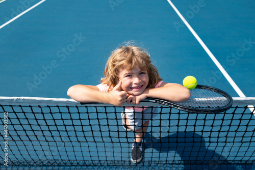 Little boy playing tennis. Sport kids, thumbs up, winner. Child with tennis racket on tennis court. Training for young kid, healthy children.