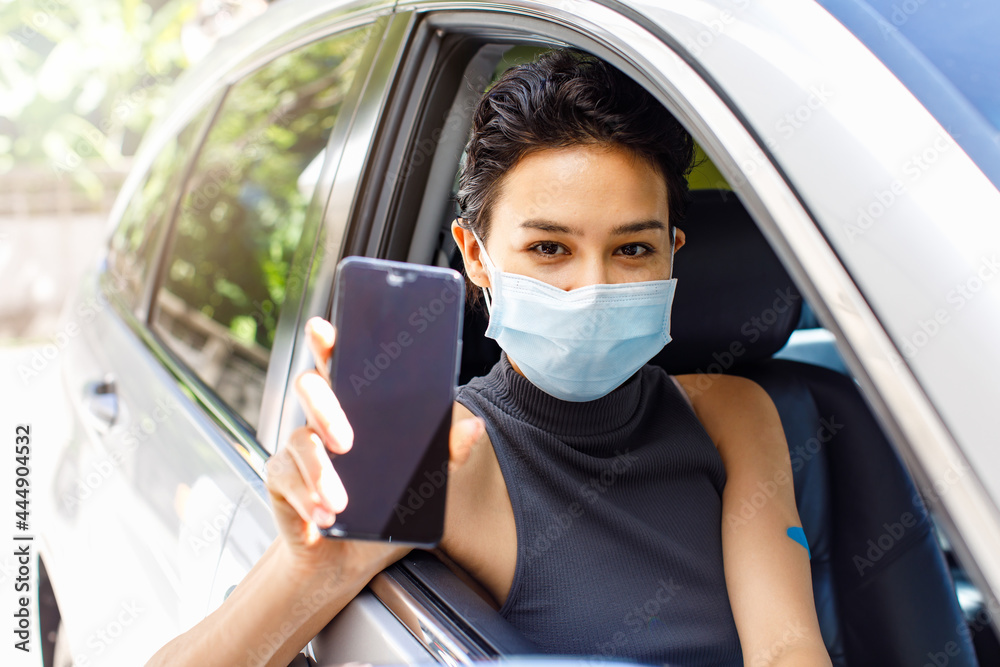 Closeup shot of blank screen mobile phone for application appointment registration copy space in female hand wearing face mask sitting in car in drive through line for coronavirus vaccination