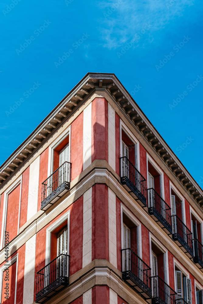 Low angle view of the corner of an old recently renovated residential building against blue sky