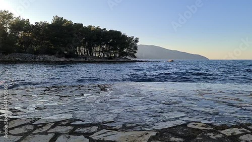 Slow Motion ocean Wave crashing on rock with sunny blue sky