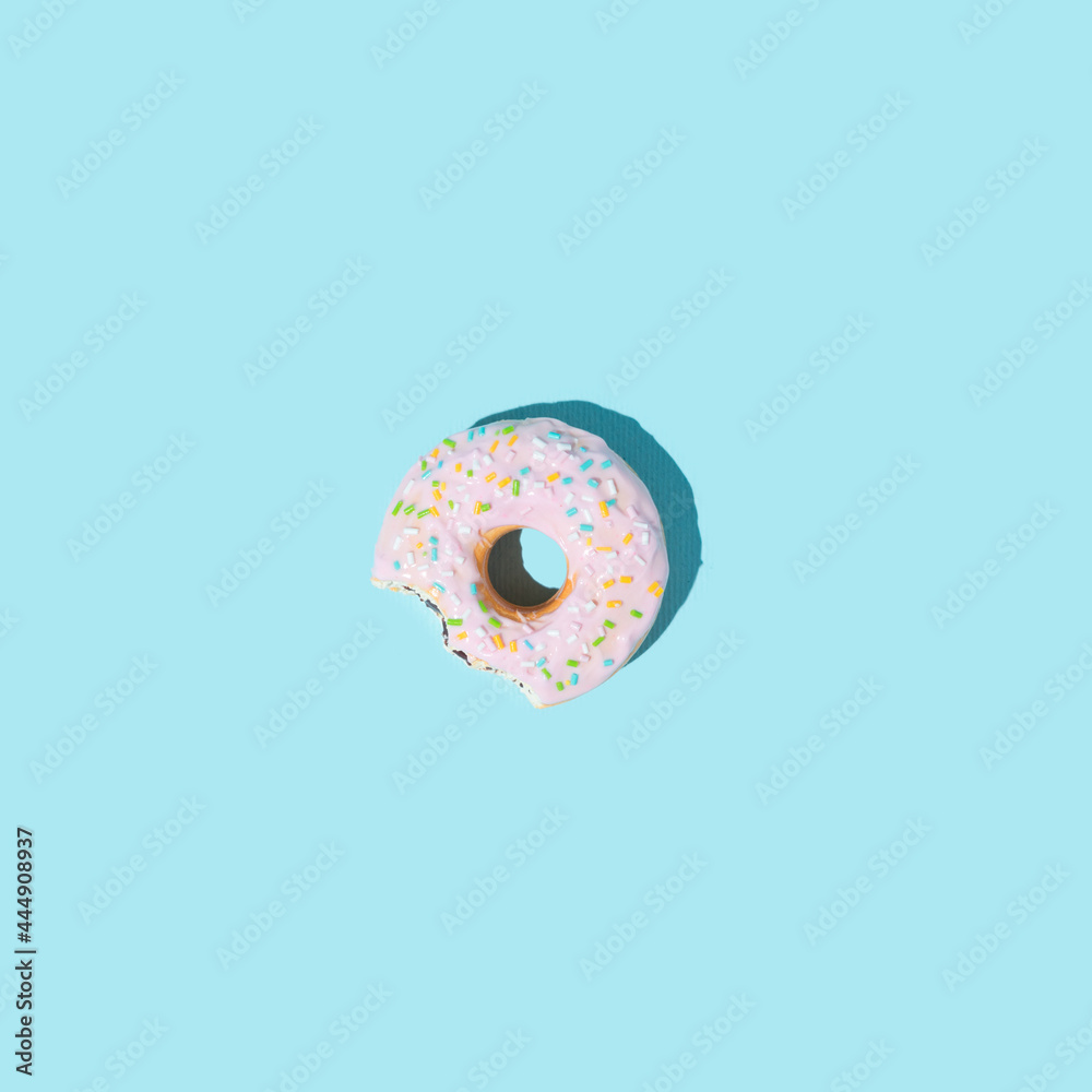 Colorful bitten donut on a pastel blue background. Minimalistic food concept. Creative summer idea. Colorful bitten donut on a pastel blue background. Minimalistic food concept. Creative summer idea.