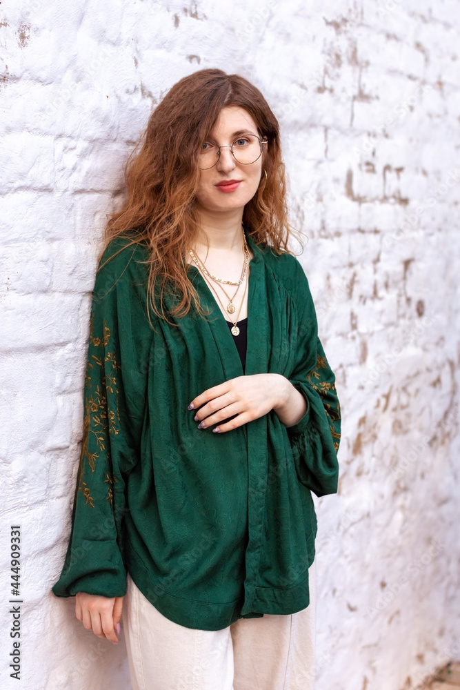 A girl in a green jacket on a white brick wall A girl in a green jacket on a white brick wall