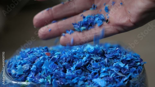 Female hand iterating blue plastic pieces lying in a transparent container 