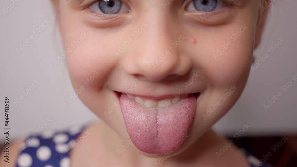 little girl pulls out long tongue. child shows his teeth and mouth to