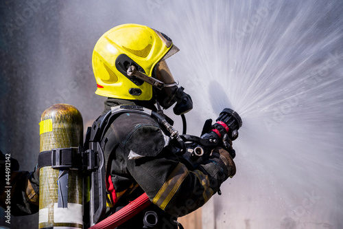 Obraz na płótnie firefighters wearing fire fighter suit for safety and using twirl water extinguisher for fighting the fire flame in emergency situation.. - Safety Firefighter and industrial concept. w salonie