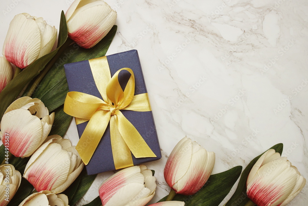 Blue Gift boxes with gold ribbon and tulip flower bouquet on marble background