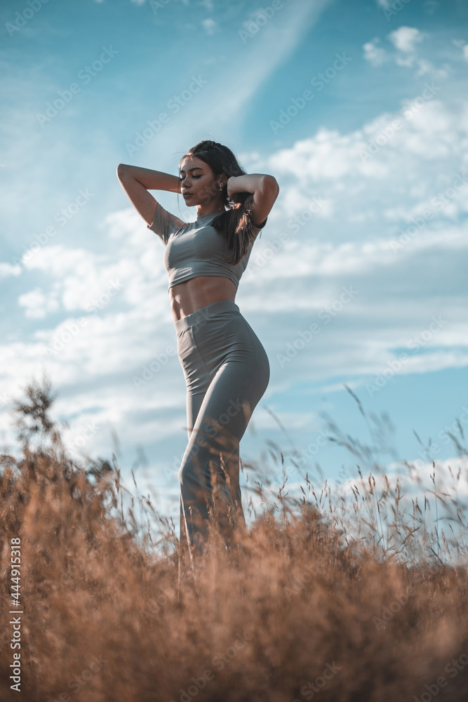 Fashion outdoor photo of beautiful woman with dark hair in luxurious sport dress posing in summer field. Fashion outdoor photo of beautiful woman with dark hair in luxurious sport dress posing in summer field.