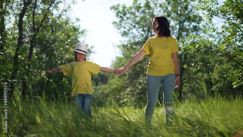 Happy family. Mom and daughter in forest park. People walk on grass. Happy team mom and daughter. Family is walk on grass in park. People walk along the tava in forest. Happy family concept photo