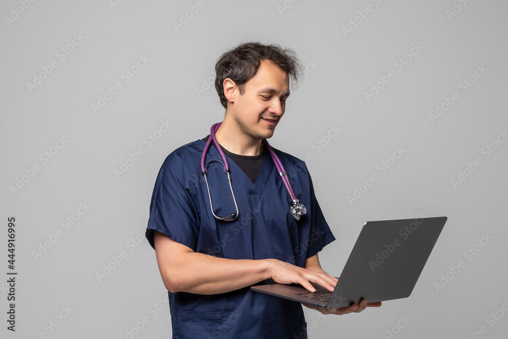Smiling doctor with stethoscope working on a laptop isolated on white background Smiling doctor with stethoscope working on a laptop isolated on white background