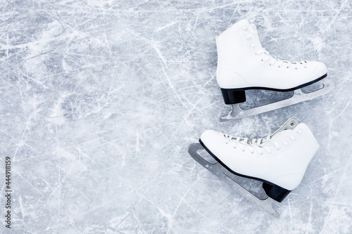 White female figure skates on ice background. Sport accessories for outdoor activities in cold winter season. Closeup. Empty place for text. Top down view.