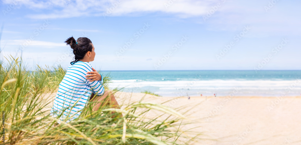 Woman at seaside in Cornwall looking at beach and waves