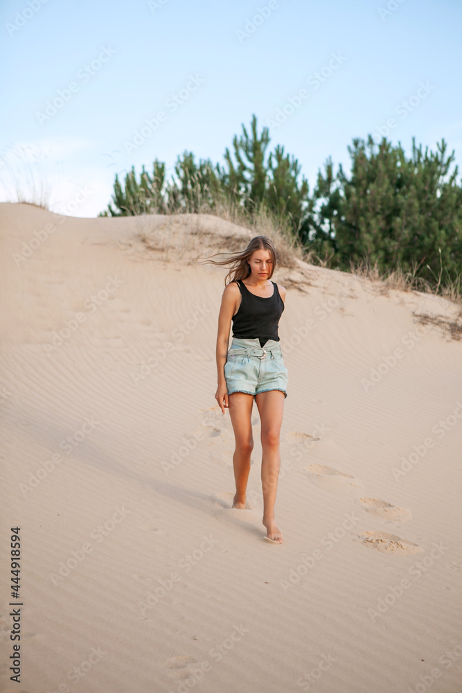woman in shorts stroll along the sand of the desert in the summer woman in shorts stroll along the sand of the desert in the summer