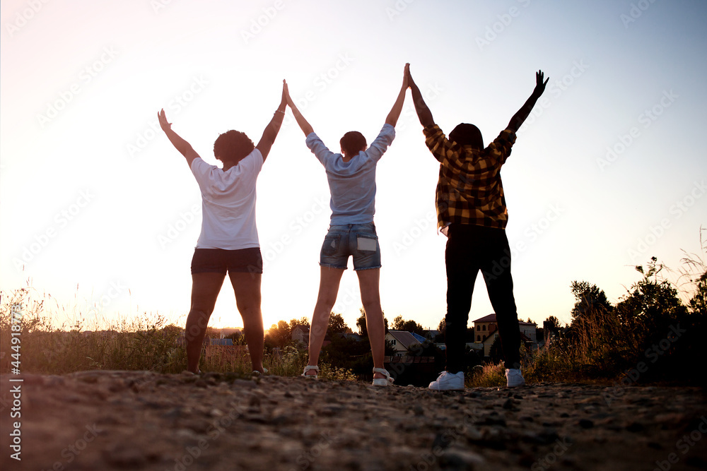 happy girls, of different nationalities, view from the back, at sunset in summer happy girls, of different nationalities, view from the back, at sunset in summer