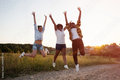 happy girls of different nationalities jump and have fun at sunset in summer