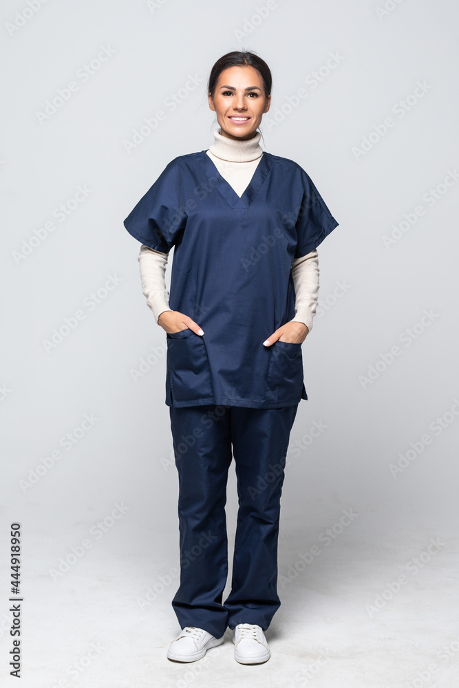 Nurse or young doctor standing smiling isolated on white background. Woman medical professional in scrubs smiling happy. Nurse or young doctor standing smiling isolated on white background. Woman medical professional in scrubs smiling happy.