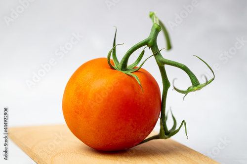 Owoc pomidora zwyczajnego leżący na drewnianej desce na białym tle. Źródło potasu.