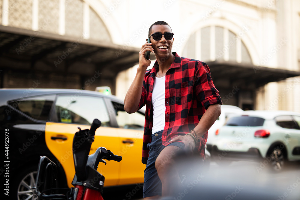 Portrait of handsome african man using electric bike in the city. Happy young man talking to the phone. Portrait of handsome african man using electric bike in the city. Happy young man talking to the phone.