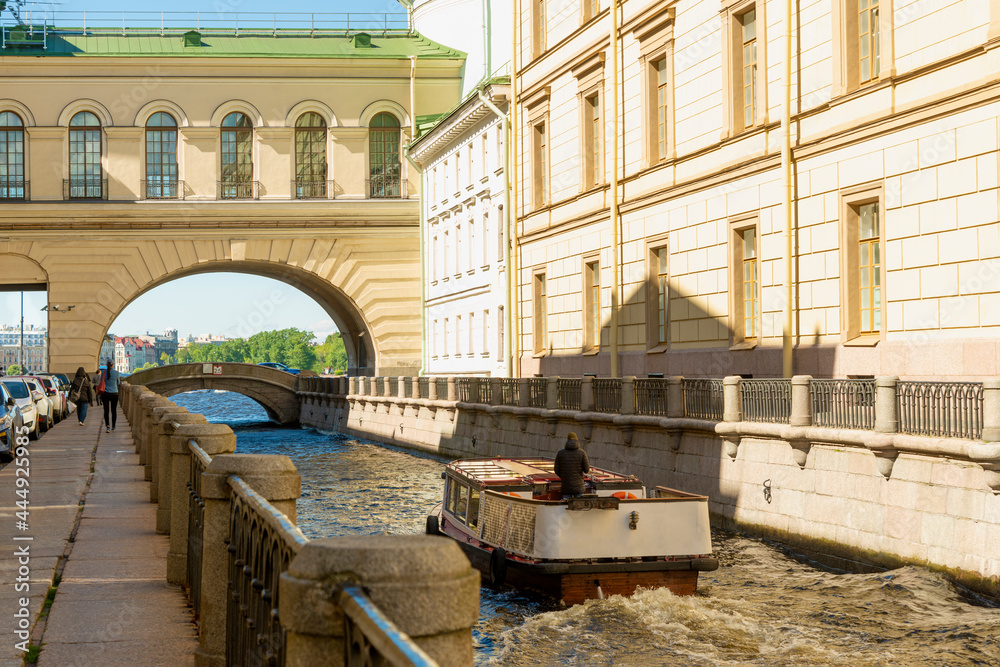 Shot of the Winter Bridge near the Hermitage in St. Petersburg in Russia in the historical part of the city. A tourist boat is sailing on the water.