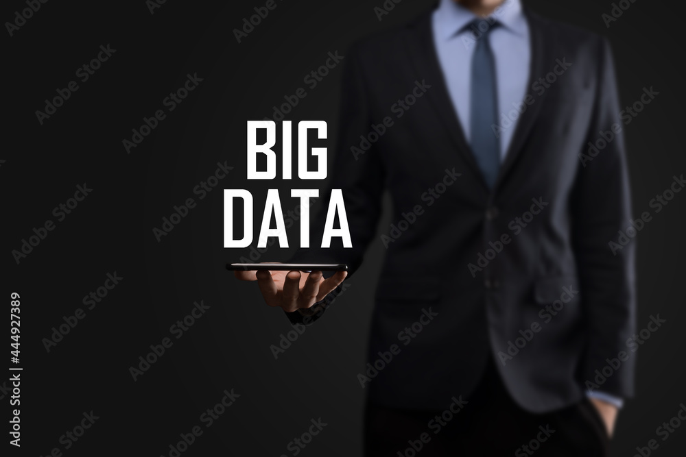 Businessman in a suit on a dark background holds the inscription BIG DATA. Storage Network Online Server Concept.Social network or business analytics representation Businessman in a suit on a dark background holds the inscription BIG DATA. Storage Network Online Server Concept.Social network or business analytics representation