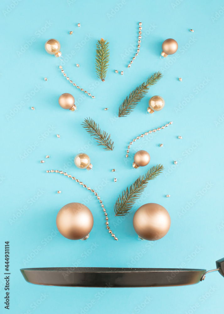 Fototapeta premium Christmas baubles with pine branches above the pan. Minimal New Year decoration concept. Flat lay background.