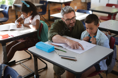 Caucasian male teacher teaching caucasian boy in the class at school