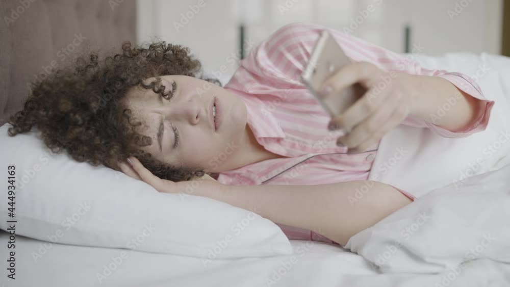 Annoyed woman waking up from alarm clock, early morning, lack of sleep Annoyed woman waking up from alarm clock, early morning, lack of sleep